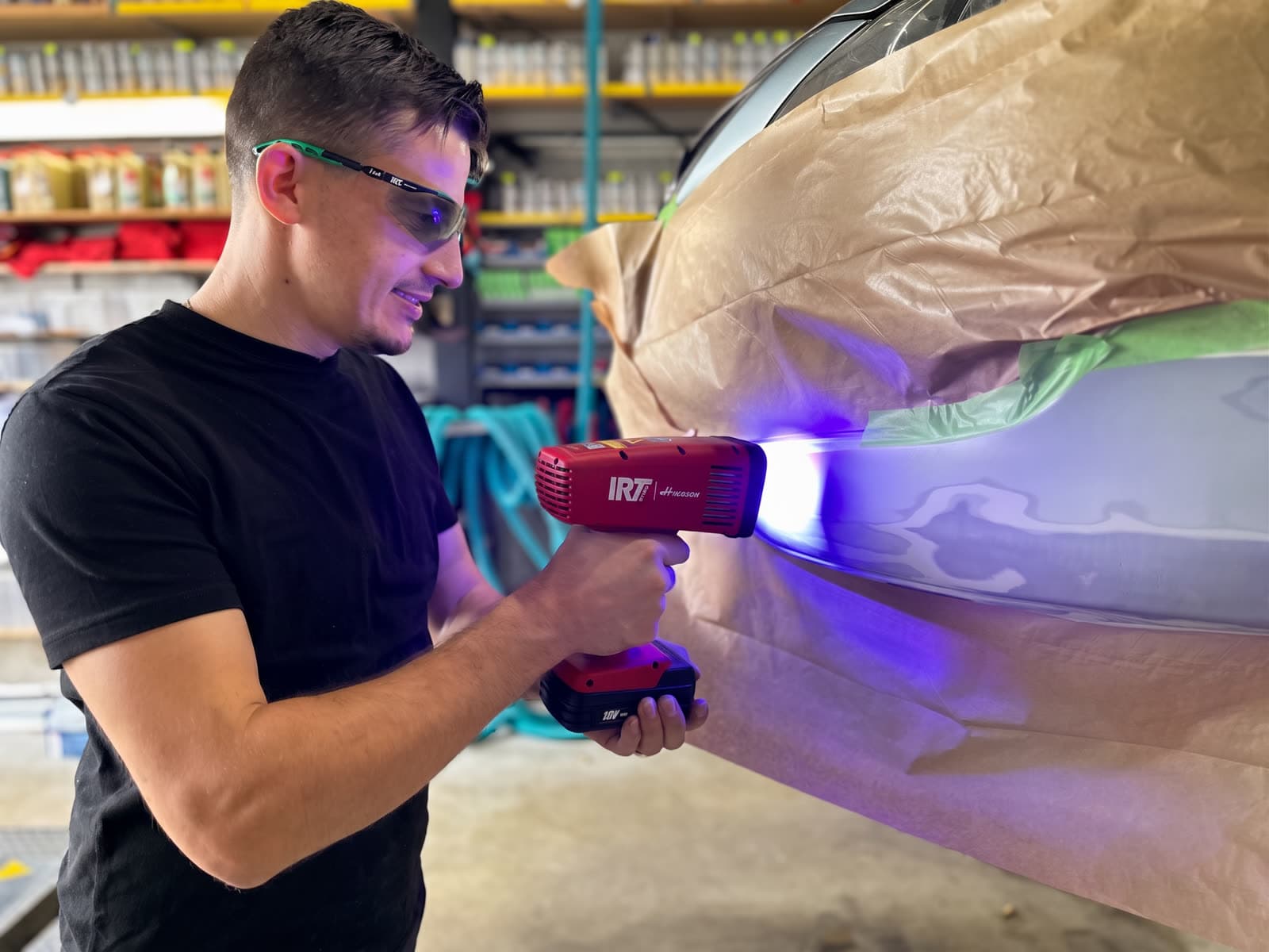 StarWash-Mitarbeiter härtet UV-Füller mit Tesla Cure ZERO LED-Lampe an einer abgeklebten Lackstelle aus