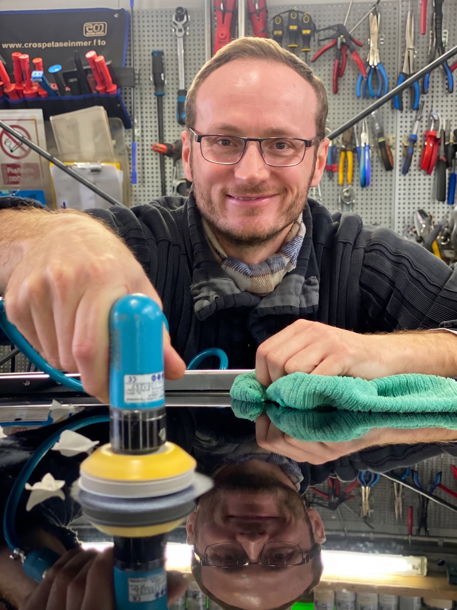 StarWash-Mitarbeiter mit Schutzbrille poliert mit Mini-Polierer und Mikrofaser-Tuch eine Lackstelle