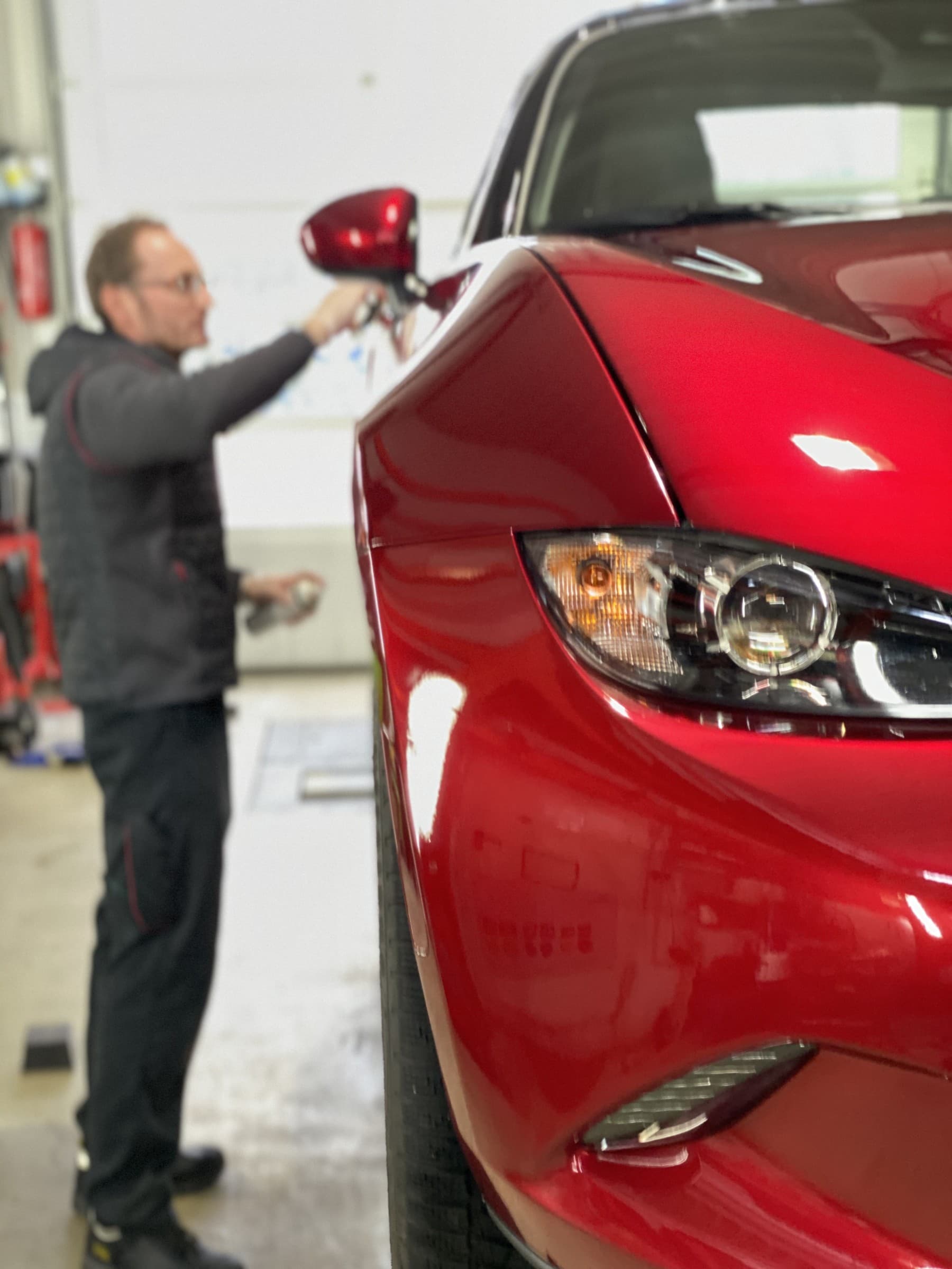 StarWash-Mitarbeiter poliert roten Mazda MX-5 in der Aufbereitung