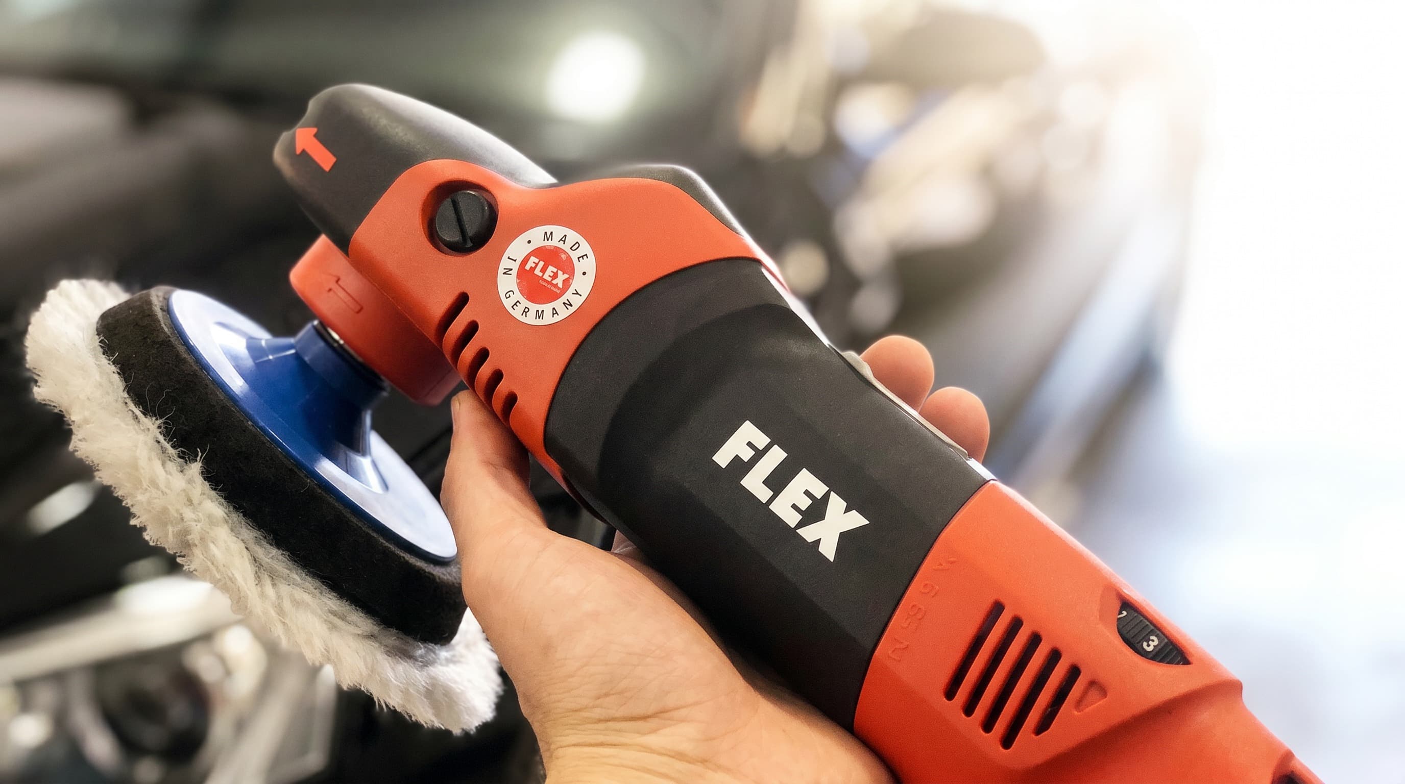 FLEX Polierer im Einsatz vor schwarzem Auto in der StarWash Aufbereitung Münster